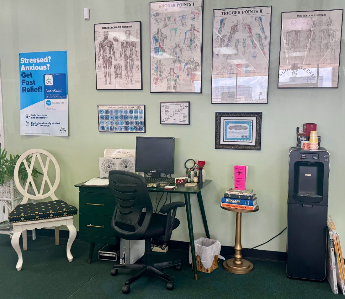 Cheryl's iridology desk with iris reference charts, anatomy posters and her certification on the wall