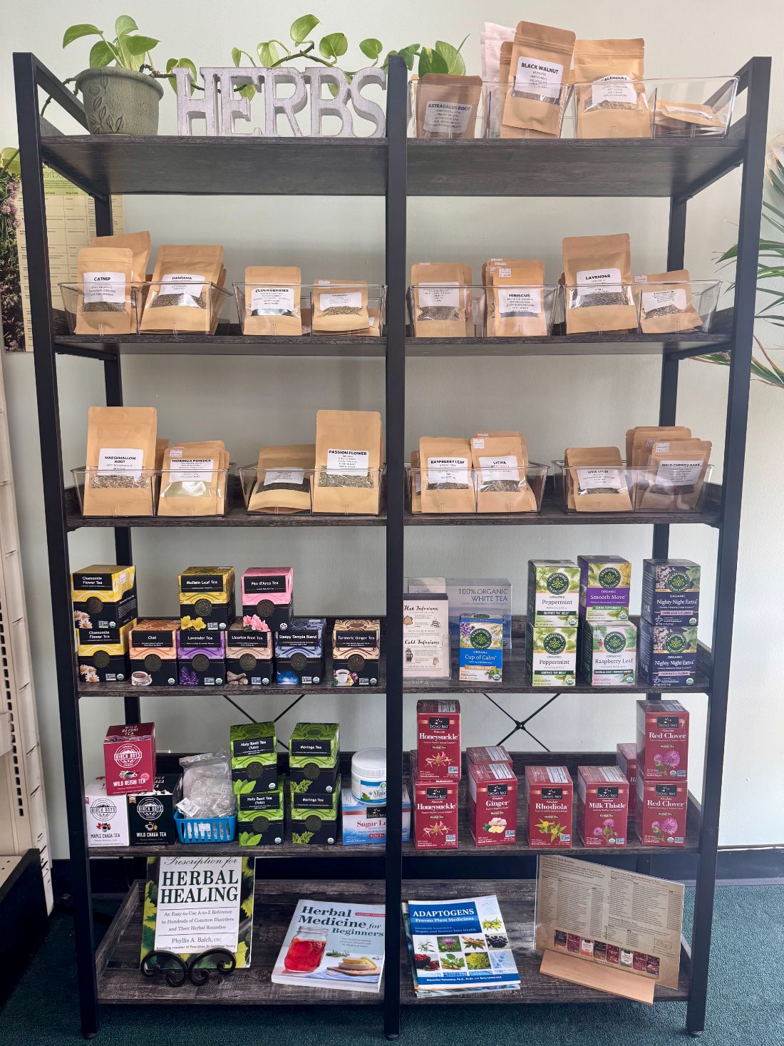 Shelves of single herbs in kraft pouches, boxed teas, and herbal reference books